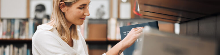 a woman takes a history book off a library shelf