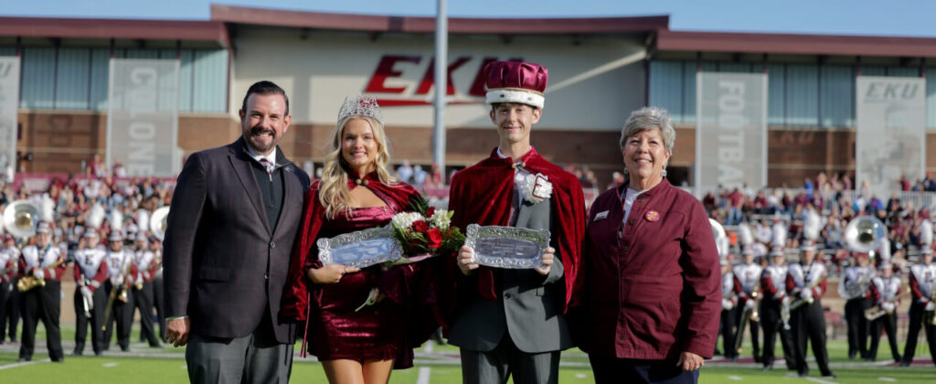 Homecoming 2024 king and queen stand with President David McFaddin on the football field at the homecoming game.