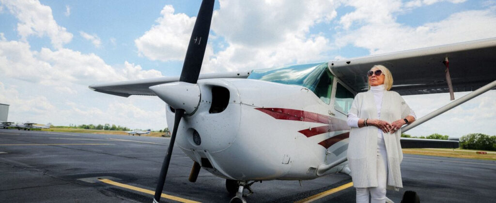 Dr. Wilma Walker stands next to a small plane.